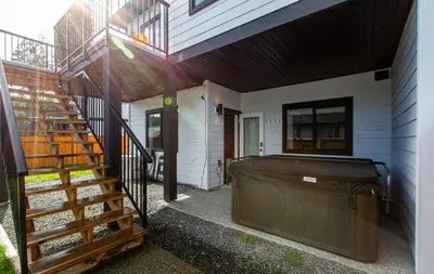 a porch of a house with a bed and stairs at Cozy Garden Suite with Hot Tub and Perfectly Located in Goldstream Station