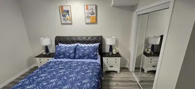 a bedroom with a bed and two dressers and a mirror at Bleniel Place - Stylish Basement Suite with Wi-Fi Netflix & Parking in Edmonton