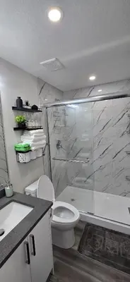 a bathroom with a shower and a toilet and a sink at Bleniel Place - Stylish Basement Suite with Wi-Fi Netflix & Parking in Edmonton