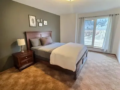 a bedroom with a large bed and a window at Spacious Getaway Two Homes on a Tranquil Vineyard Ideal for Large Groups in Keremeos