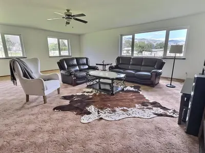 a living room with leather furniture and a table at Spacious Getaway Two Homes on a Tranquil Vineyard Ideal for Large Groups in Keremeos