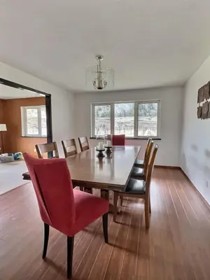 a dining room with a wooden table and red chairs at Spacious Getaway Two Homes on a Tranquil Vineyard Ideal for Large Groups in Keremeos