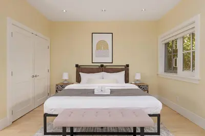 a bedroom with a large bed and two windows at Charming Luxury Home near DT and Lonsdale Quay in North Vancouver