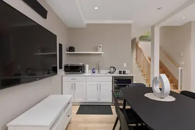 a kitchen with white cabinets and a black table at Charming Luxury Home near DT and Lonsdale Quay in North Vancouver
