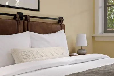 a bed with a white pillow on top of it at Charming Luxury Home near DT and Lonsdale Quay in North Vancouver