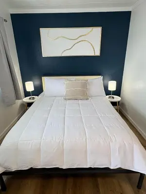 a bedroom with a large white bed with two side tables at Remo Stays in Unity
