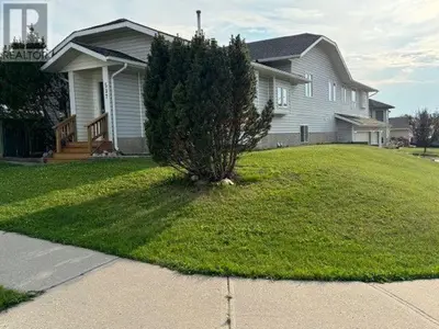 a house with a tree in the front yard at Alpenglow Oasis in Hinton