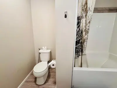a white bathroom with a toilet and a shower at Sunlit Haven in Calgary