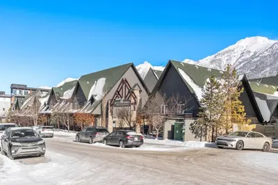 a snowy street with cars parked in front of a building at 2BR Mystic Springs Escape with BBQ, Pool, Hot tub in Canmore