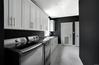 a kitchen with white cabinets and a dishwasher at Shawnigan Lake Retreat with Theatre in Shawnigan Lake