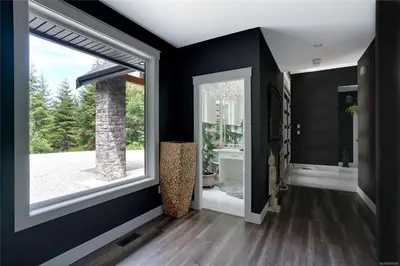 a hallway with black walls and a bathroom with a window at Shawnigan Lake Retreat with Theatre in Shawnigan Lake