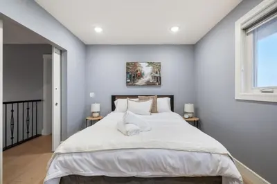 a bedroom with a large white bed with two tables at The Royal Ravine Luxury Retreat with Hot Tub & Sauna in Calgary