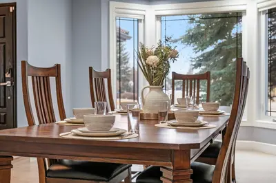 a wooden table with chairs and a vase with flowers at The Royal Ravine Luxury Retreat with Hot Tub & Sauna in Calgary