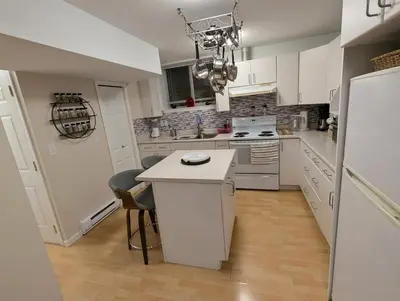 a kitchen with white cabinets and a white island at Walnut Grove Gem in Langley