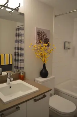 a bathroom with a sink and a vase with yellow flowers at Be Close To Chinatown When You Are In The Union Building in Victoria