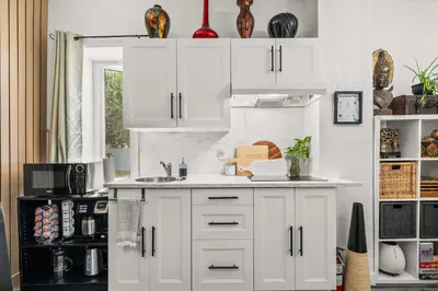 a kitchen with white cabinets and a sink at Downtown Den - Steps Away from Worlds Largest Dino in Drumheller
