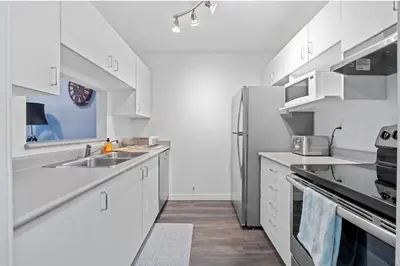 a kitchen with white cabinets and a stainless steel refrigerator at Cozy 1 Bedroom Downtown Central in Vancouver
