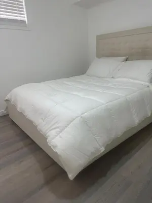 a white bed with white sheets and pillows at 2bedroom, 2bed day light Suite in a nice and secured neighborhood in Prince George