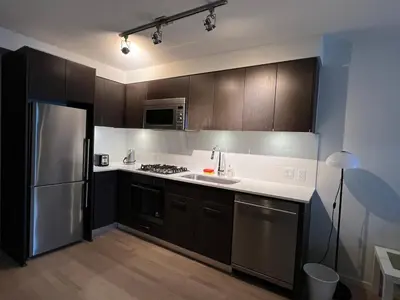 a kitchen with brown cabinets and a stainless steel refrigerator at Cozy Perfect &elegant 2bed 1 bath in Richmond center in Richmond