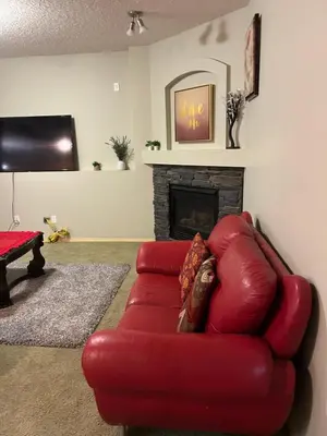 a red leather couch in a living room with a fireplace at Unique home services in Bélanger
