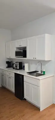 a white kitchen with white cabinets and a sink at New Royal Inn in New Westminster