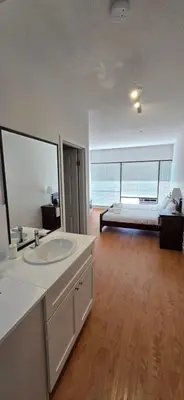 a bathroom with a sink and a bed in a room at New Royal Inn in New Westminster
