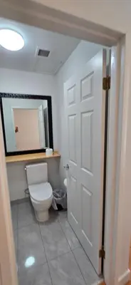 a bathroom with a white toilet and a mirror at New Royal Inn in New Westminster