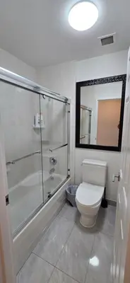 a bathroom with a toilet and a glass shower at New Royal Inn in New Westminster