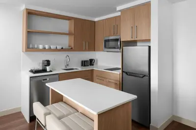 a kitchen with wooden cabinets and a black refrigerator at Element Calgary Downtown by Westin in Calgary