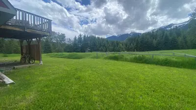a field of green grass with a balcony on a house at Pet Friendly 3 Bdrm Home with Hot Tub by StayIn in Fernie