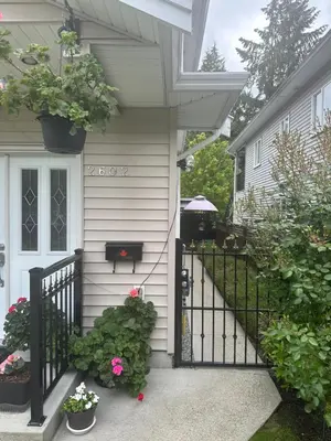 a house with a black fence and flowers at Clean and Quiet 2 bdr 2 bthr private entrance entire guests suite near Coquitlam Center mall and skytrain in Coquitlam