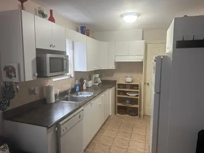 a kitchen with white cabinets and a sink and a refrigerator at Clean and Quiet 2 bdr 2 bthr private entrance entire guests suite near Coquitlam Center mall and skytrain in Coquitlam