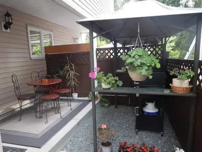 a patio with an umbrella and a table and chairs at Clean and Quiet 2 bdr 2 bthr private entrance entire guests suite near Coquitlam Center mall and skytrain in Coquitlam