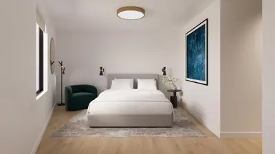a white bedroom with a bed and a green chair at The Como Hotel in Vancouver