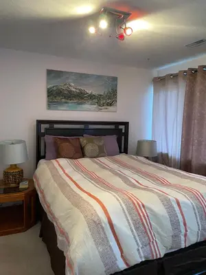 a bedroom with a bed with two lamps and a painting at Imperial Ranchettes GuestSuite in Lone Butte
