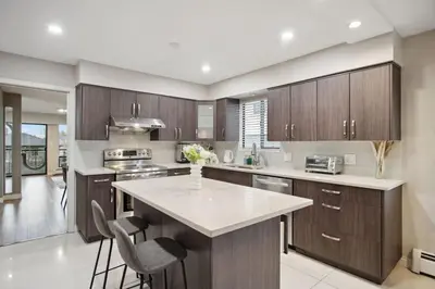 a kitchen with wooden cabinets and a large island at 6 Bedroom Family Home with Indoor Arcade, BBQ, Huge Backyard & Pickleball in Vancouver