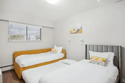two beds in a room with white walls at 6 Bedroom Family Home with Indoor Arcade, BBQ, Huge Backyard & Pickleball in Vancouver