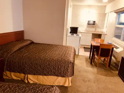 a bedroom with a bed and a table and a kitchen at Red Carpet Inn & Suites in Calgary