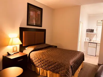 a hotel room with a bed and a table at Red Carpet Inn & Suites in Calgary