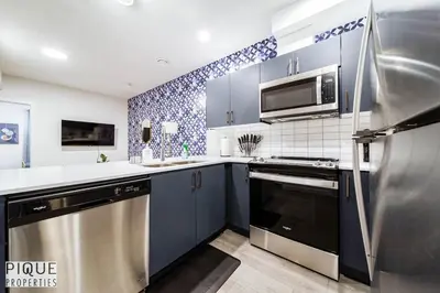 a kitchen with blue cabinets and a stainless steel refrigerator at NEW-The Suite Life-2BD-King Bed-WEM & YEG Airport in Edmonton
