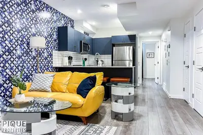 a living room with a yellow couch and a kitchen at NEW-The Suite Life-2BD-King Bed-WEM & YEG Airport in Edmonton