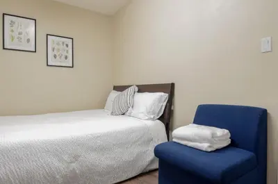 a bedroom with a bed and a blue chair at Close to YVR! Convenient 3BR Stay for Every Occasion in Vancouver