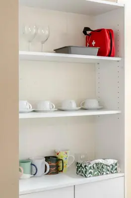 a shelf with dishes and glasses and a red bag at Close to YVR! Convenient 3BR Stay for Every Occasion in Vancouver
