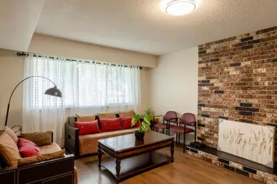 a living room with a couch and a brick wall at Close to YVR! Convenient 3BR Stay for Every Occasion in Vancouver