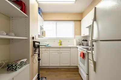 a kitchen with white cabinets and a refrigerator at Close to YVR! Convenient 3BR Stay for Every Occasion in Vancouver