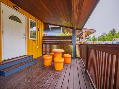 a porch with a table and three orange stools at Surf Haven - Cabin in Ucluelet - Sleeps 5 in Ucluelet
