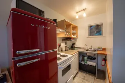 a red refrigerator in a kitchen with a stove at Surf Haven - Cabin in Ucluelet - Sleeps 5 in Ucluelet