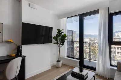 a living room with a tv and large windows at Keefer House in Vancouver