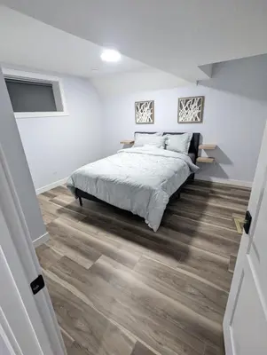 a bedroom with a bed and a wooden floor at Chic 2BR Suite with Kitchen, Laundry, Near Elk Island & West Edmonton Mall in Edmonton