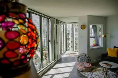 a living room with a couch and a room with windows at Luxury Ocean view Apartment- Heart of Yaletown Downtown Vancouver in Vancouver